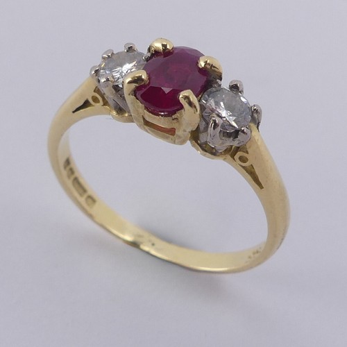 190 - A three stone ruby and diamond Ring, the central oval facetted ruby 5.9mm with a small circular diam... 