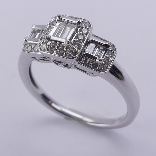 193 - A contemporary graduated triple cluster diamond Ring, each cluster with two baguette diamonds to the... 