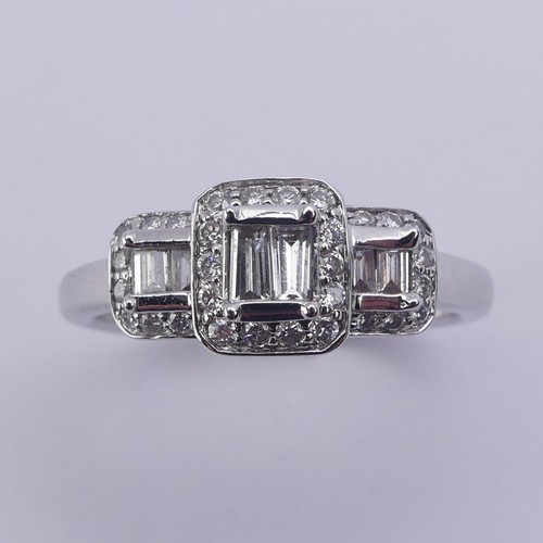 193 - A contemporary graduated triple cluster diamond Ring, each cluster with two baguette diamonds to the... 