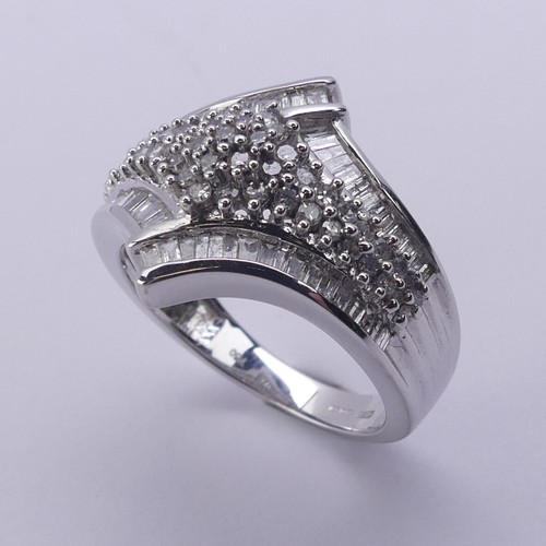 200 - A contemporary diamond Dress Ring, the flared front with central pavé set cluster within a ba... 