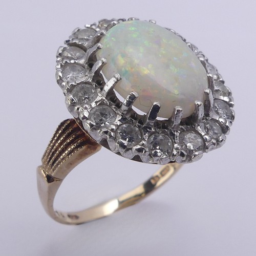 226 - An opal and diamond cluster Ring, the central oval opal 12mm long surrounded by sixteen circular dia... 