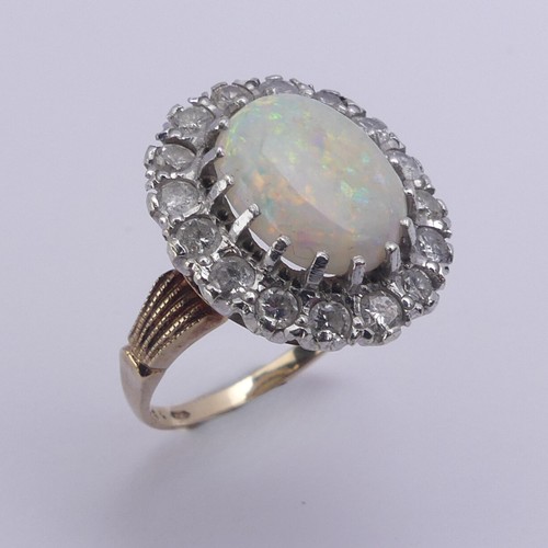 226 - An opal and diamond cluster Ring, the central oval opal 12mm long surrounded by sixteen circular dia... 