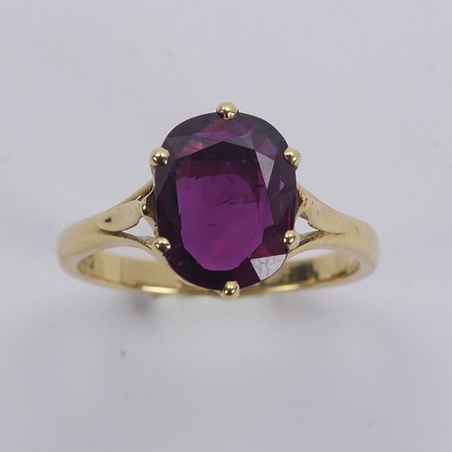 227 - A single stone ruby Ring, the striking oval cushion shaped stone with purple hues, six claw set in 1... 