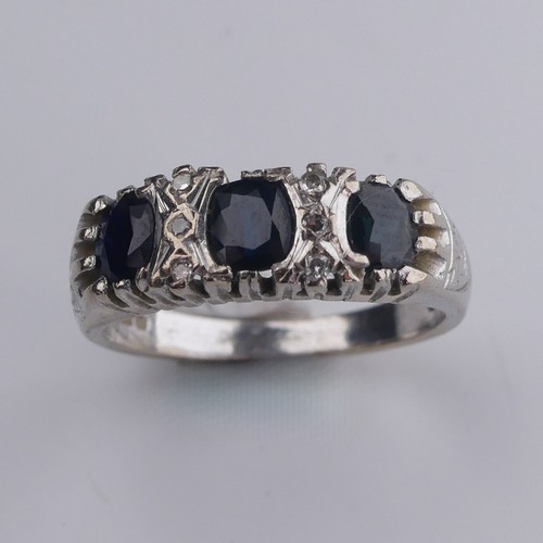 176 - A three stone sapphire Ring, the cushion shaped facetted stones with three diamond points vertically... 