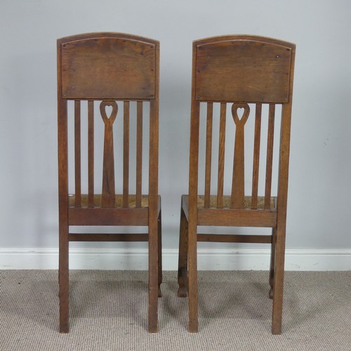 523 - In the manner of Liberty a pair of Arts and Crafts oak Hall Chairs, rush headrests over spindle back... 