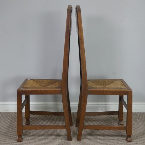 523 - In the manner of Liberty a pair of Arts and Crafts oak Hall Chairs, rush headrests over spindle back... 