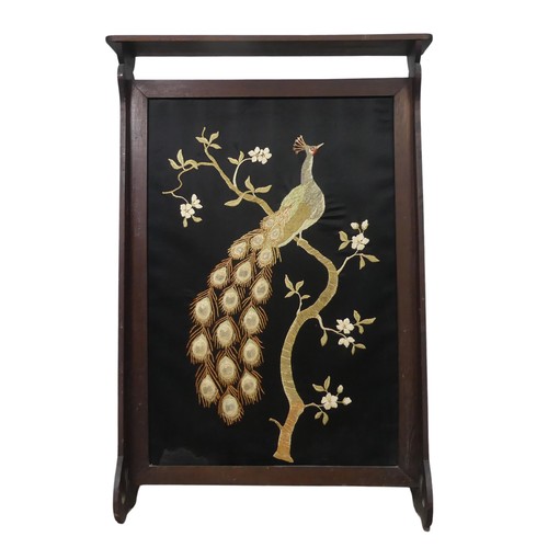 556 - An Arts and Crafts oak framed fire Screen, with centrally embroidered panel depicting a peacock, W 6... 