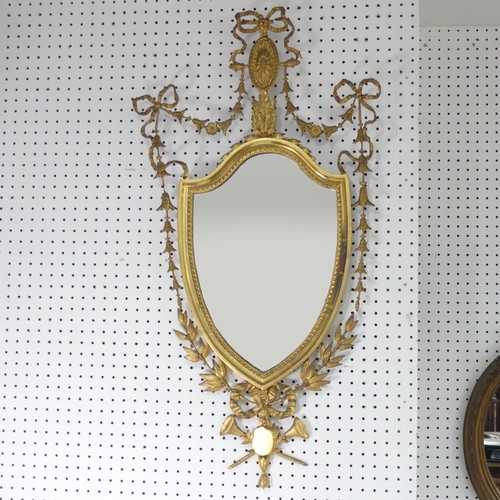 510 - A giltwood framed wall Mirror in George III style, the frame decorated with foliate swags and bows, ... 