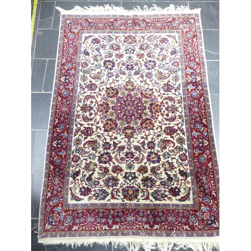 704 - Tribal Rugs; a Persian Isfahan rug, finely knotted wool pile on cotton base, cream ground within a r... 