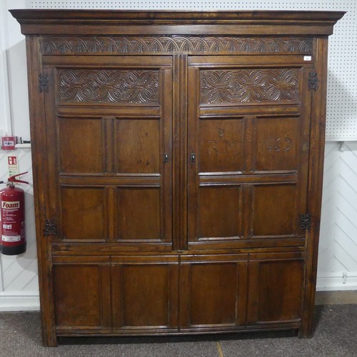 666 - A 17th century and later carved oak hall Cupboard, the carved and moulded cornice over two large pan... 