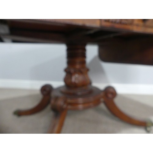 549 - A Regency mahogany and rosewood banded Sofa Table, raised on carved column and quadraform reeded sup... 