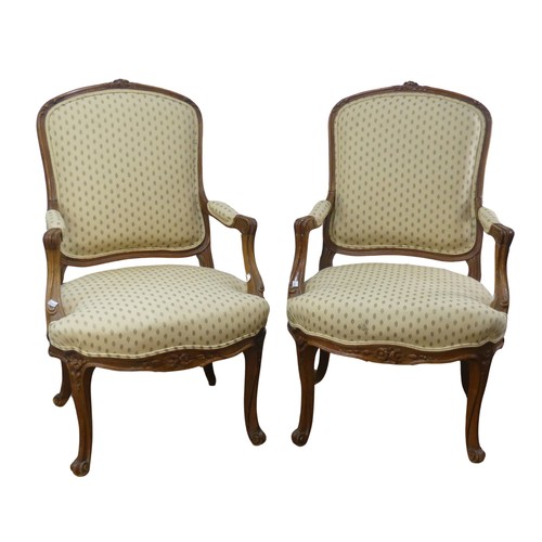 696 - A pair of French Louis XV style walnut Armchairs, the upholstered backrest and seat flanked by scrol... 