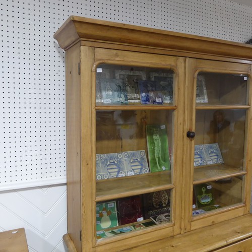 688 - A Victorian pine Dresser, the moulded cornice over two glazed doors, concealing shelves, raised on b... 