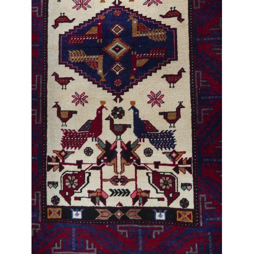 710 - Tribal Rugs: a Persian 'animal' rug, the cream and red ground woven with stylised peacocks and birds... 