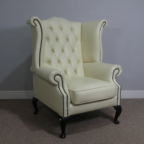 522 - A cream leather button and wingback Armchair, W 89 cm x H 90 cm x D 90 cm.