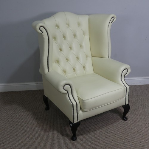 522 - A cream leather button and wingback Armchair, W 89 cm x H 90 cm x D 90 cm.