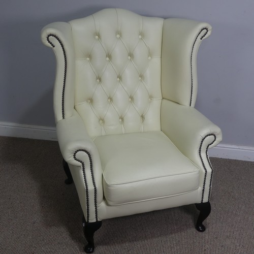 522 - A cream leather button and wingback Armchair, W 89 cm x H 90 cm x D 90 cm.