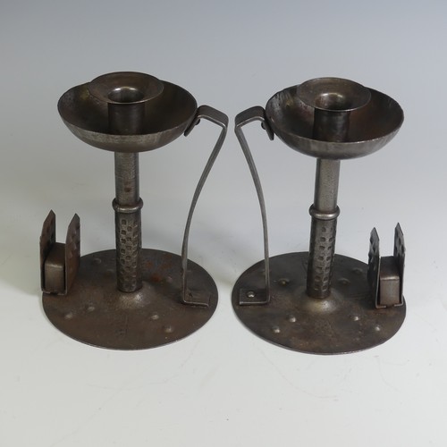 531 - A pair of Arts and Crafts steel Chamber Candlesticks, with angular handles, the flat bases with matc... 