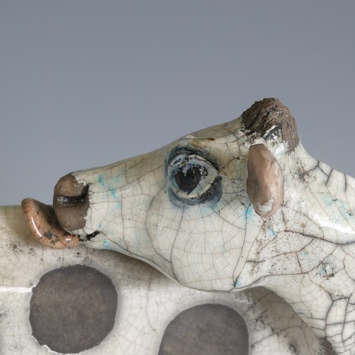 367 - Lawson E. Rudge (b. 1936), a raku fired pottery sculpture of a licking Flat Cow, spot pattern and nu... 