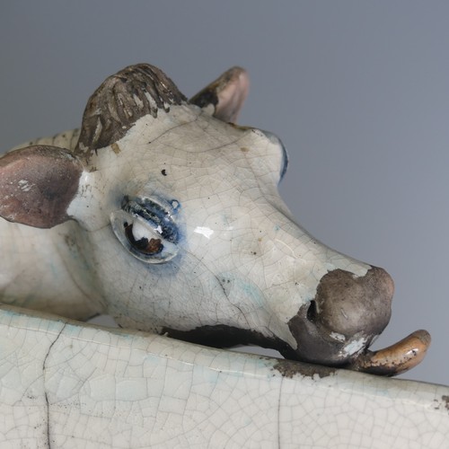 367 - Lawson E. Rudge (b. 1936), a raku fired pottery sculpture of a licking Flat Cow, spot pattern and nu... 