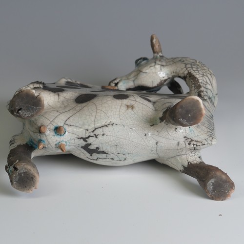 367 - Lawson E. Rudge (b. 1936), a raku fired pottery sculpture of a licking Flat Cow, spot pattern and nu... 