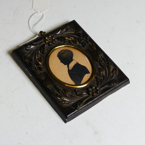 390 - An oval silhouette of a young man, 19th century, heightened with gilt, mounted in an embossed metal ... 