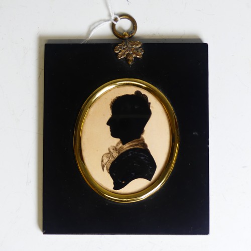 390 - An oval silhouette of a young man, 19th century, heightened with gilt, mounted in an embossed metal ... 