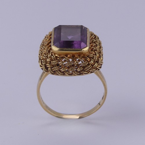 134 - An amethyst Dress Ring, the emerald cut stone approx. 11.6mm x 9.2mm, collet set within an elaborate... 