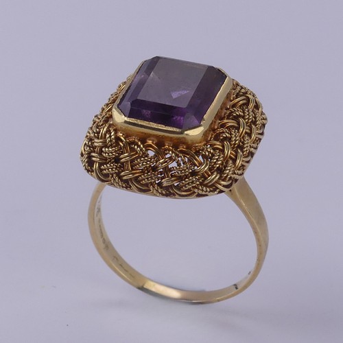 134 - An amethyst Dress Ring, the emerald cut stone approx. 11.6mm x 9.2mm, collet set within an elaborate... 