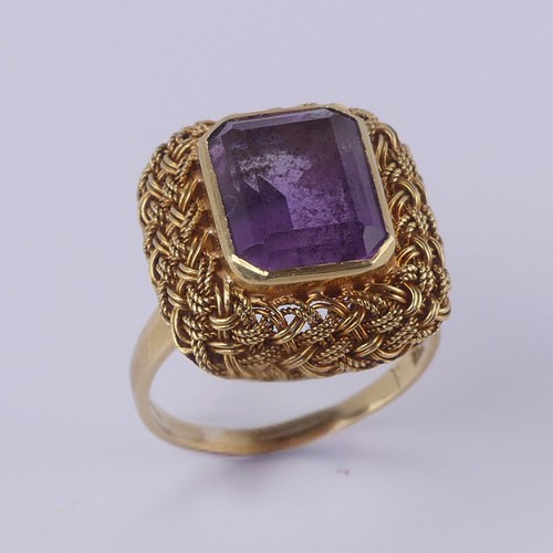 134 - An amethyst Dress Ring, the emerald cut stone approx. 11.6mm x 9.2mm, collet set within an elaborate... 