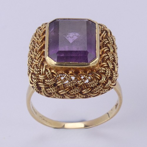 134 - An amethyst Dress Ring, the emerald cut stone approx. 11.6mm x 9.2mm, collet set within an elaborate... 