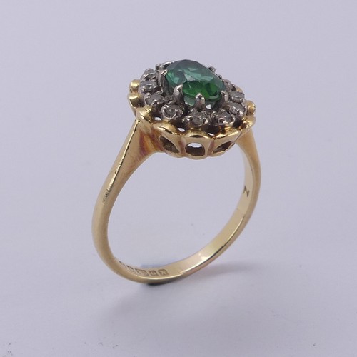 161 - A demantoid garnet and diamond cluster Ring, the oval facetted garnet, approx. 6.8mm long, surrounde... 