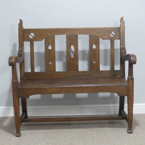 606 - In the manner of Liberty & co an Arts and Crafts oak Settle, backrest with pierced yin-yang moti... 