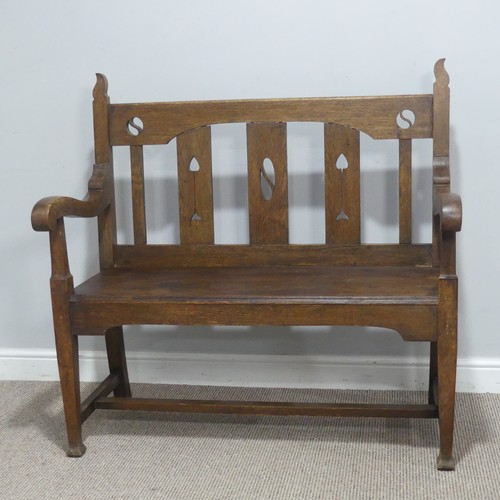 606 - In the manner of Liberty & co an Arts and Crafts oak Settle, backrest with pierced yin-yang moti... 