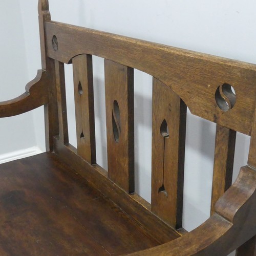 606 - In the manner of Liberty & co an Arts and Crafts oak Settle, backrest with pierced yin-yang moti... 