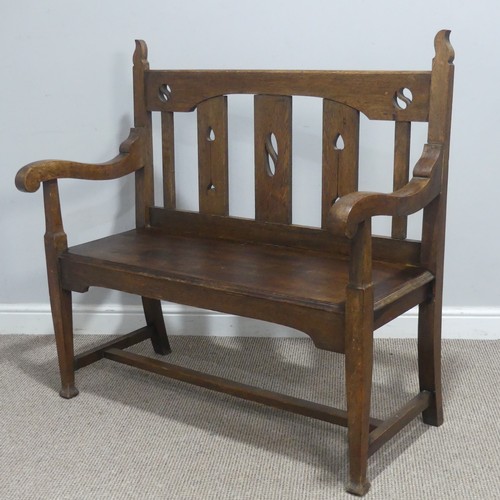 606 - In the manner of Liberty & co an Arts and Crafts oak Settle, backrest with pierced yin-yang moti... 