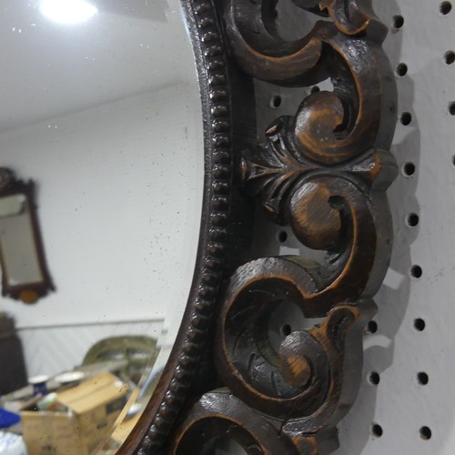 671 - An antique carved oak circular wall Mirror, the carved scrolled frame encasing beveled mirror, W 70 ... 