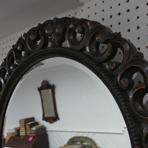 671 - An antique carved oak circular wall Mirror, the carved scrolled frame encasing beveled mirror, W 70 ... 