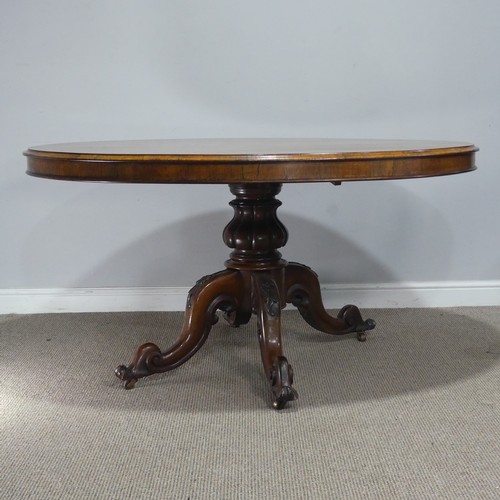 688 - A Victorian rosewood tilt-top Table, the oval top raised on carved and turned column and quadraform ... 