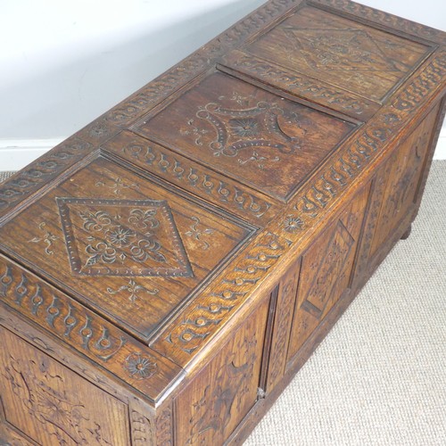 747 - An early 19th century carved oak Coffer, the hinged top over carved paneled sides, raised on turned ... 