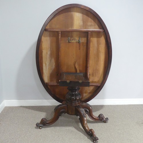 688 - A Victorian rosewood tilt-top Table, the oval top raised on carved and turned column and quadraform ... 