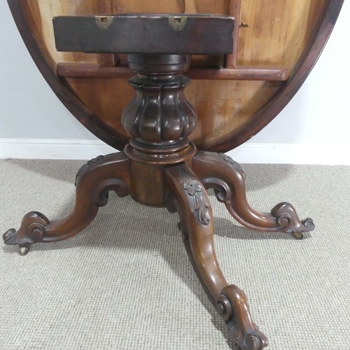 688 - A Victorian rosewood tilt-top Table, the oval top raised on carved and turned column and quadraform ... 