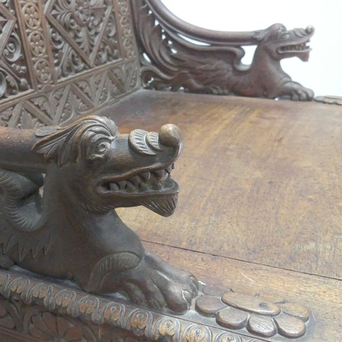 745 - A Victorian carved oak box Seat/Settle, decorated with scrolled pierced foliage and with carved drag... 