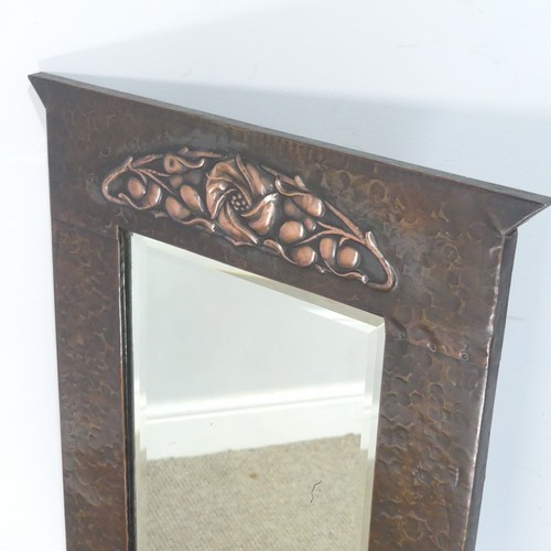 571 - An Arts and Crafts rectangular copper Mirror, the hammered frame with shaped top above stylised foli... 