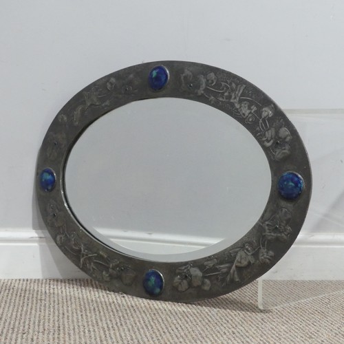 A rare Liberty & Co pewter oval Mirror, the frame having four ruskin cabochons between embossed fish amongst stylised flowers, the flower heads with green glass cabochons, the reverse with ivorine label for "LIBERTY, LONDON", W 65 cm x H 47 cm.