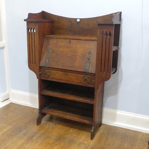 735 - An Arts and Crafts Liberty & co style students desk Bureau, the central fall front flanked by sh... 