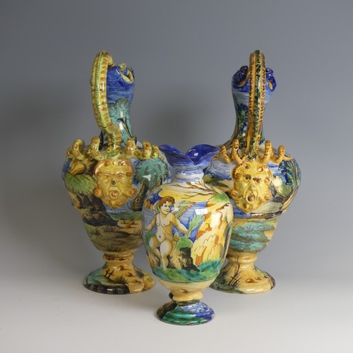 27 - A near matched pair of Italian majolica Ewers, decorated with scenes of cherubs in lakeside mountain... 