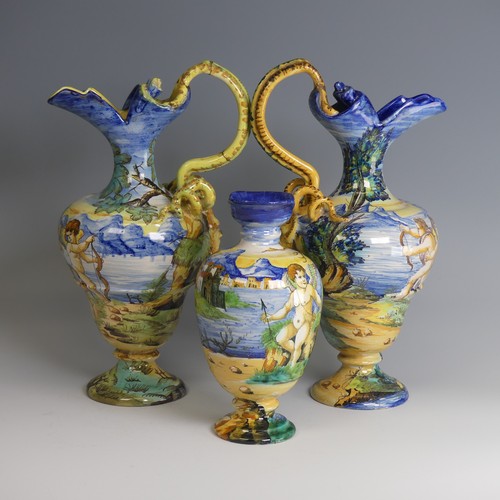 27 - A near matched pair of Italian majolica Ewers, decorated with scenes of cherubs in lakeside mountain... 