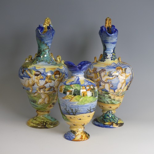 27 - A near matched pair of Italian majolica Ewers, decorated with scenes of cherubs in lakeside mountain... 