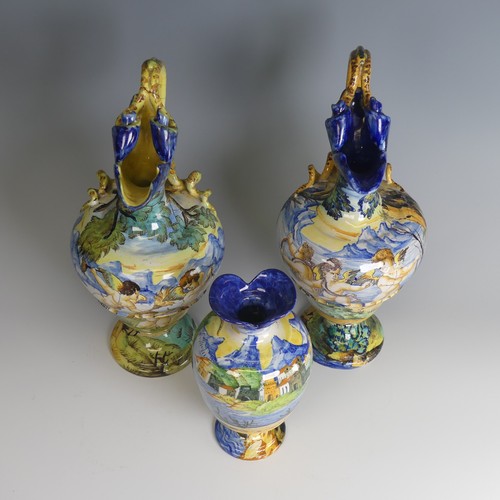 27 - A near matched pair of Italian majolica Ewers, decorated with scenes of cherubs in lakeside mountain... 